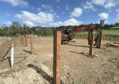 Construction site with excavator and steel posts in a line on cleared ground